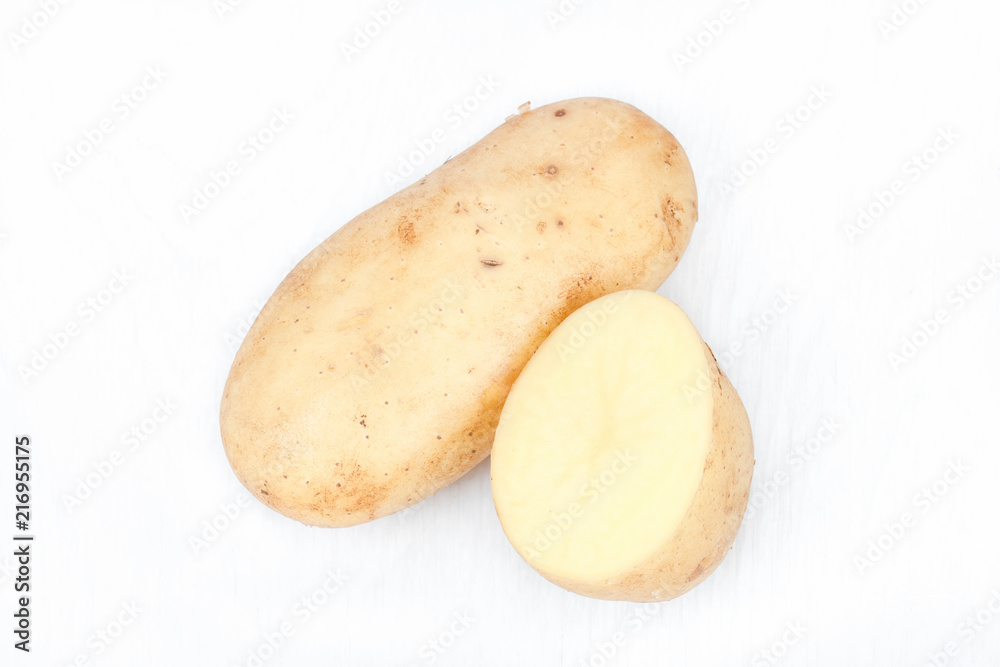 New harvest. Potatoes from the own garden. Ecologically, biological, healthy, delicious. Stack of brown/ yellow potatoes with half of it. Young potato isolated on white background. Closeup. Top view.