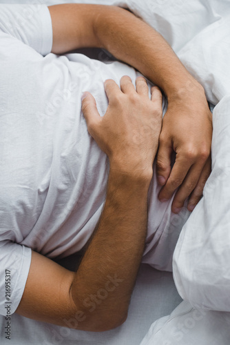 cropped shot of man suffering from abdominal pain in bed