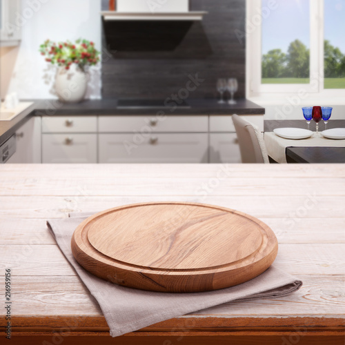 Empty wooden table with pizza board and tablecloth near the window in kitchen. White Napkin close up top view mock up. Kitchen rustic background.