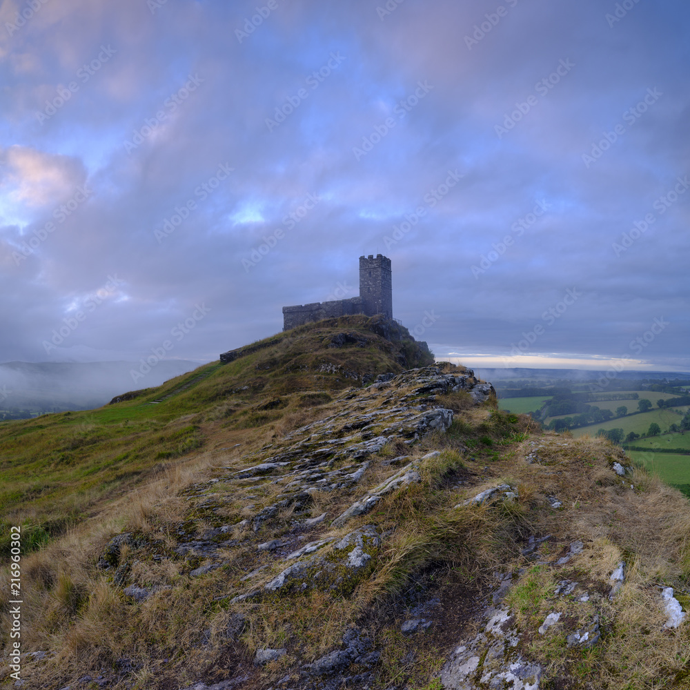 Summer sunrise on Brentor showning St Michael's church atop the tor with dramatic weather clouds of showers and mist, on the western edge of the Dartmoor National Park. UK