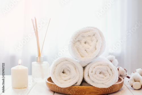 Clean white towels on the wooden tray, candle and aroma diffuser.