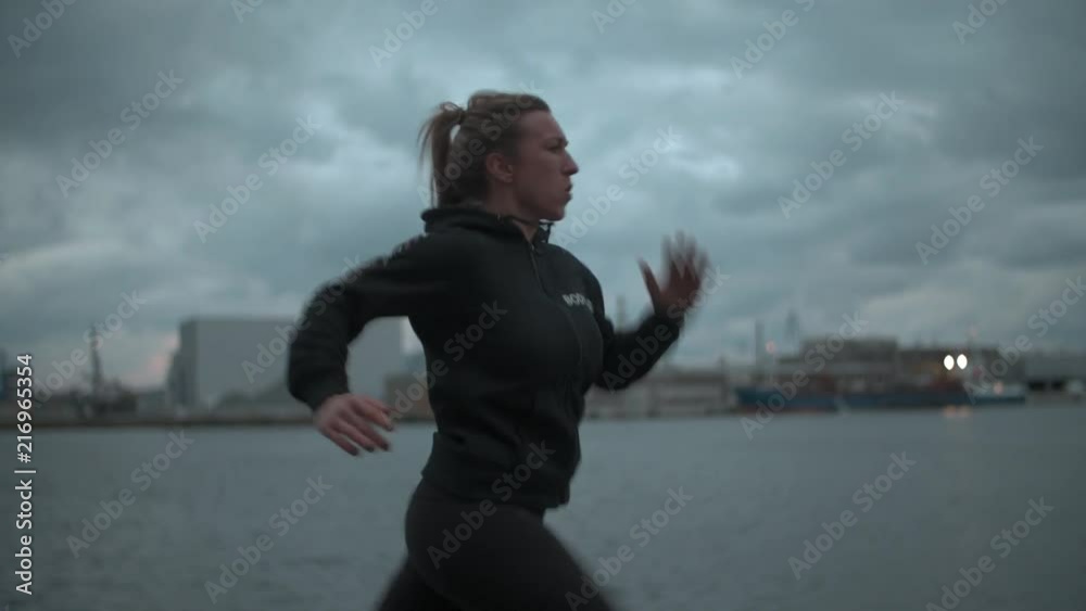 Girl running on harbor, pushing herself to her max.