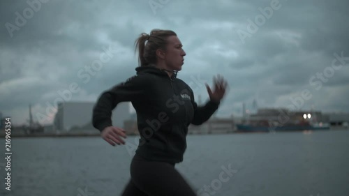 Girl running on harbor, pushing herself to her max.