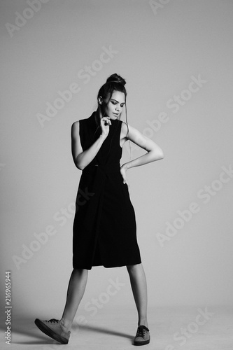 girl in a black suit with a hat, hair posing in the Studio on a gray background. black and white photo