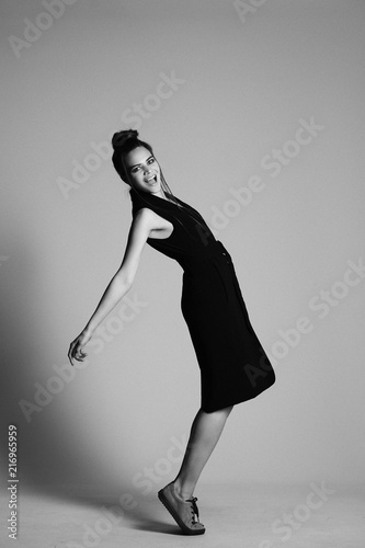 girl in a black suit with a hat, hair posing in the Studio on a gray background. black and white photo