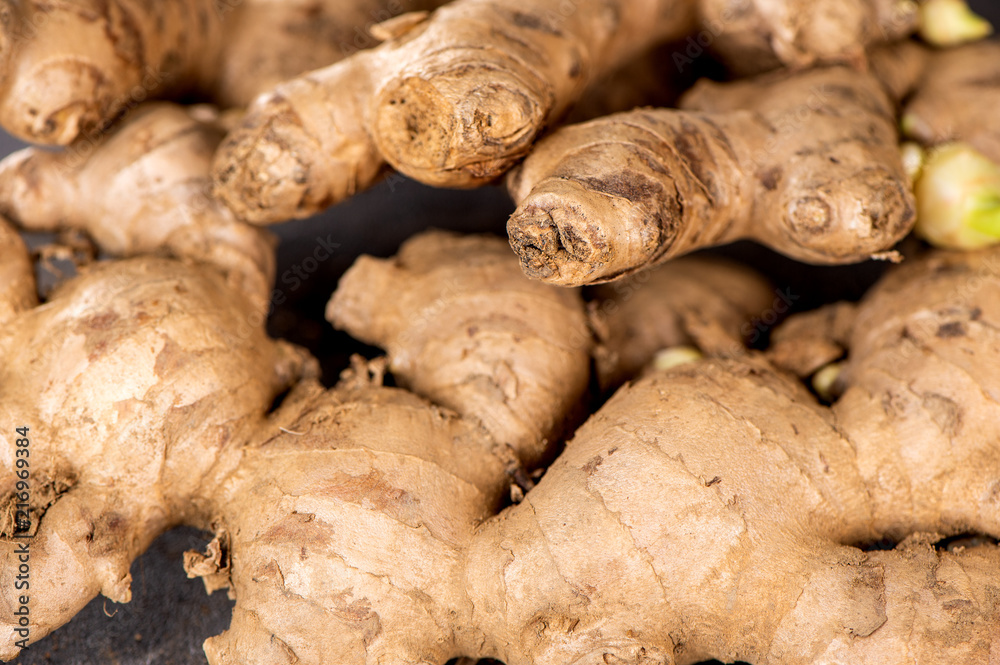 Whole ginger roots on dark old stone background table top view space for text.