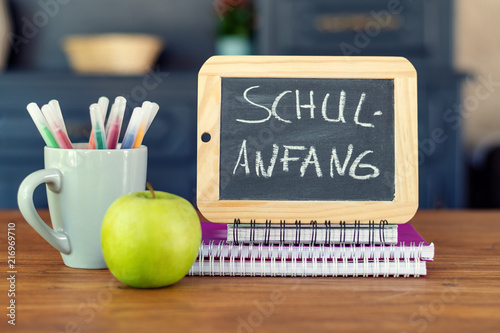Back to school. Concept with pens, books, an apple and blackboard with inscription : Back to school (in german) photo