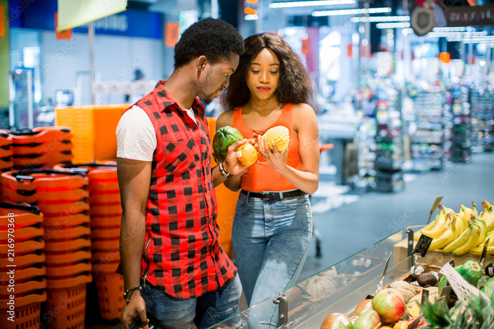 African couple shopping in supermarket produce department