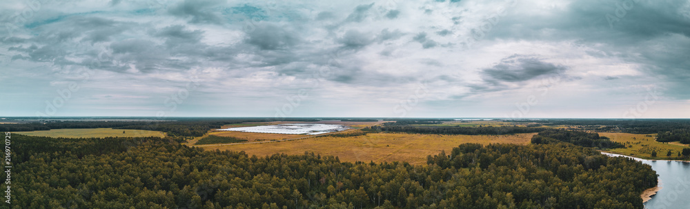 Aerial drone panoramic view of fields landscape, deep mixed forest, planting in greenhouses on the background, long panoramic photo in autumn evening in harvest season, South Ural, Russia