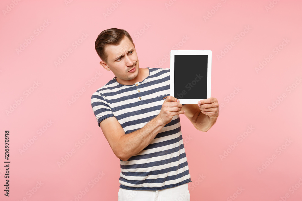 Portrait of young man holding tablet computer with blank black empty screen display touchscreen copy space isolated on trending pastel pink background. Technology lifestyle concept. Advertising area. Portrait of young man holding tablet computer with blank black empty screen display touchscreen copy space isolated on trending pastel pink background. Technology lifestyle concept. Advertising area.