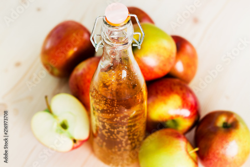 Bottle of fresh apple cider and half apple near autumn apples