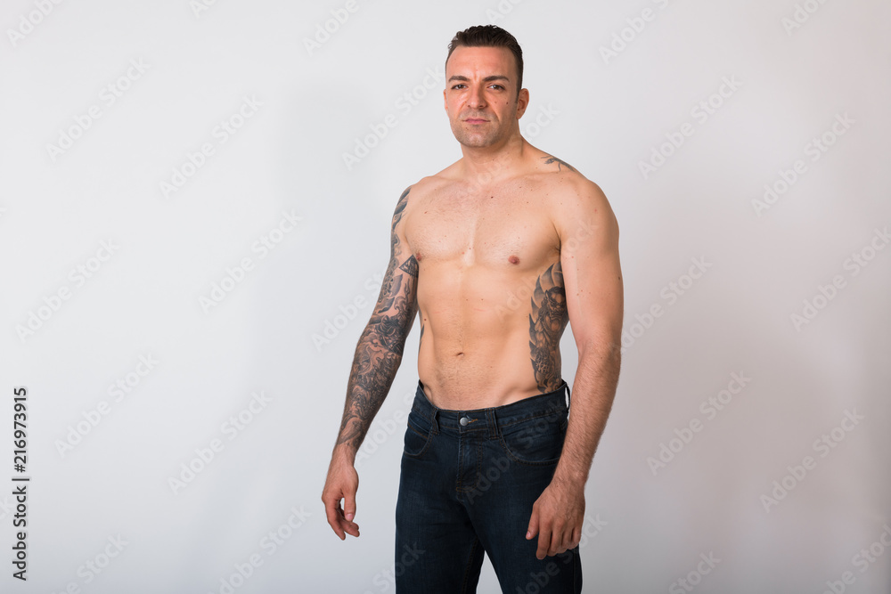 Portrait Of Shirtless Man With Tattoos Against White Background