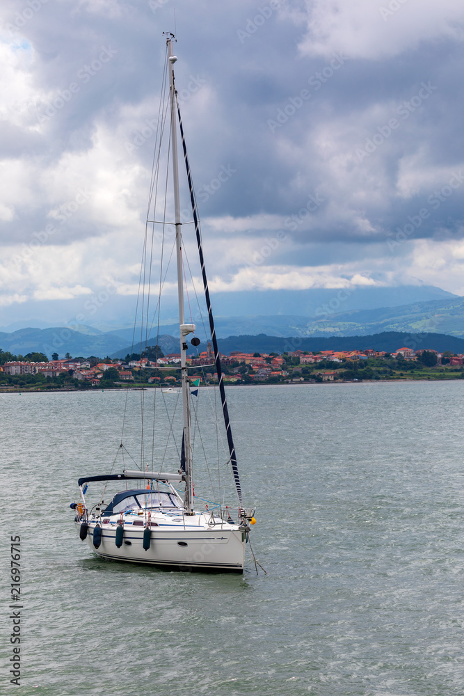 Sport sail boat moored in bay with calm sea and threatening sky. Sport sail boat moored in bay with calm sea and threatening sky.