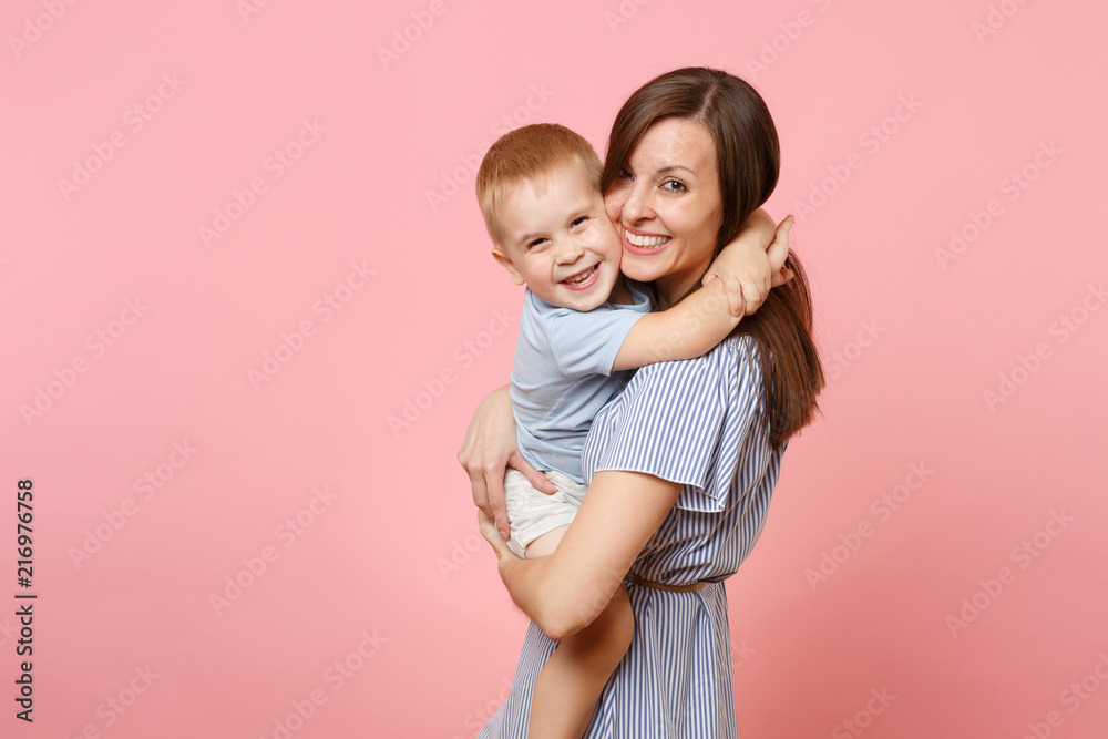 Portrait happy young family. Mother keep in arms, tender embrace, gently hugs child kid son baby boy on pastel pink background. Sincere emotions, fondness, Mother's Day, parenthood, childhood concept. Portrait happy young family. Mother keep in arms, tender embrace, gently hugs child kid son baby boy on pastel pink background. Sincere emotions, fondness, Mother's Day, parenthood, childhood concept.