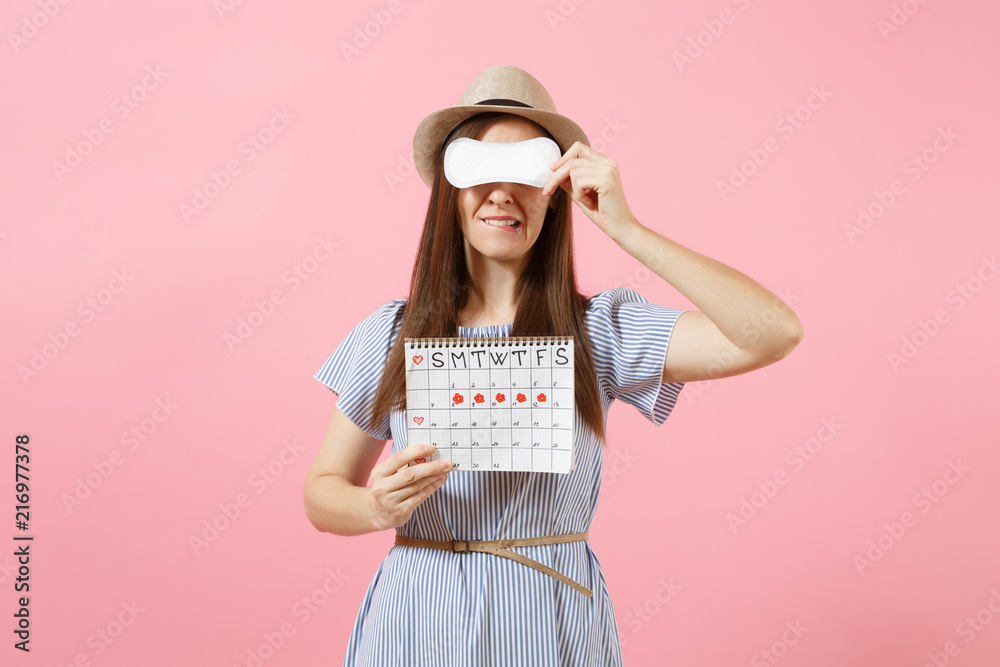 Woman in blue dress, hat holding sanitary napkin, cover eyes, female periods calendar for checking menstruation days isolated on pink background. Medical, healthcare, gynecological concept. Copy space Woman in blue dress, hat holding sanitary napkin, cover eyes, female periods calendar for checking menstruation days isolated on pink background. Medical, healthcare, gynecological concept. Copy space