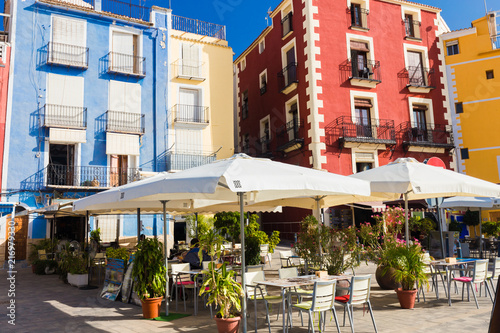 Cafe, colorful houses and palms on the street in Villajoyosa, Spain on a sunny day photo