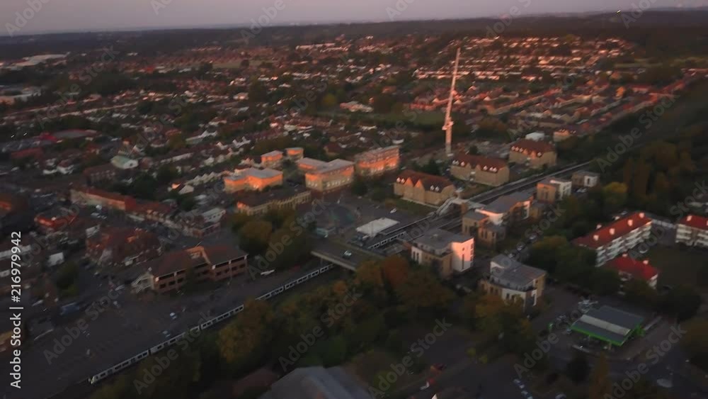 Train going left to right tracked by drone going through Borehamwood North London UK rural town. Sunset golden hour. Train going left to right tracked by drone going through Borehamwood North London UK rural town. Sunset golden hour.