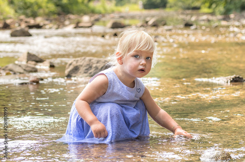 Fototapeta Naklejka Na Ścianę i Meble -  Little girl is playing with water in a river.