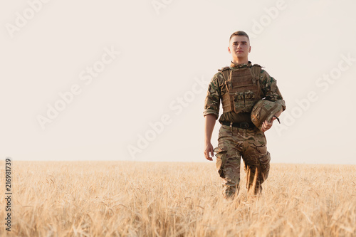 Soldier man standing against a field. Portrait of happy military soldier in boot camp. US Army soldier in the Mission. war and emotional concept. photo