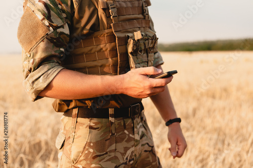 Mid section of military soldier using mobile phone in boot camp. letter from war.