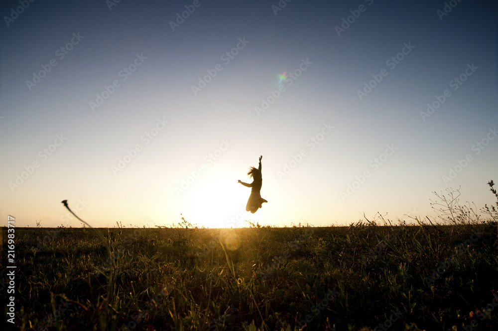 man or woman in silhouette against the sunset jumping and having fun. happiness and freedom concept for people enjoy the outdoor leisure activity