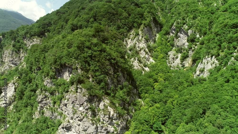 Aerial view of a person crossing the forest through a large zip line cable. Aerial view of a person crossing the forest through a large zip line cable.