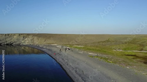 People on desolate Vaygach Island in desert of Arctic Ocean. Wilderness of Russian North. Wildlife on background of water surface. Calm wild nature of New Earth for ecotourism. photo