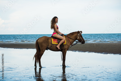 Pretty young lady riding a horse on the beach background of the sea