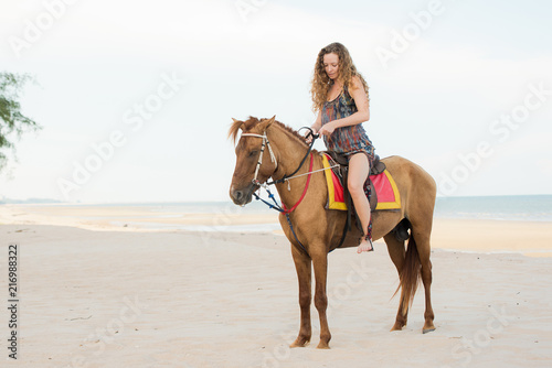 Pretty young lady riding a horse on the beach background of the sea © ic36006