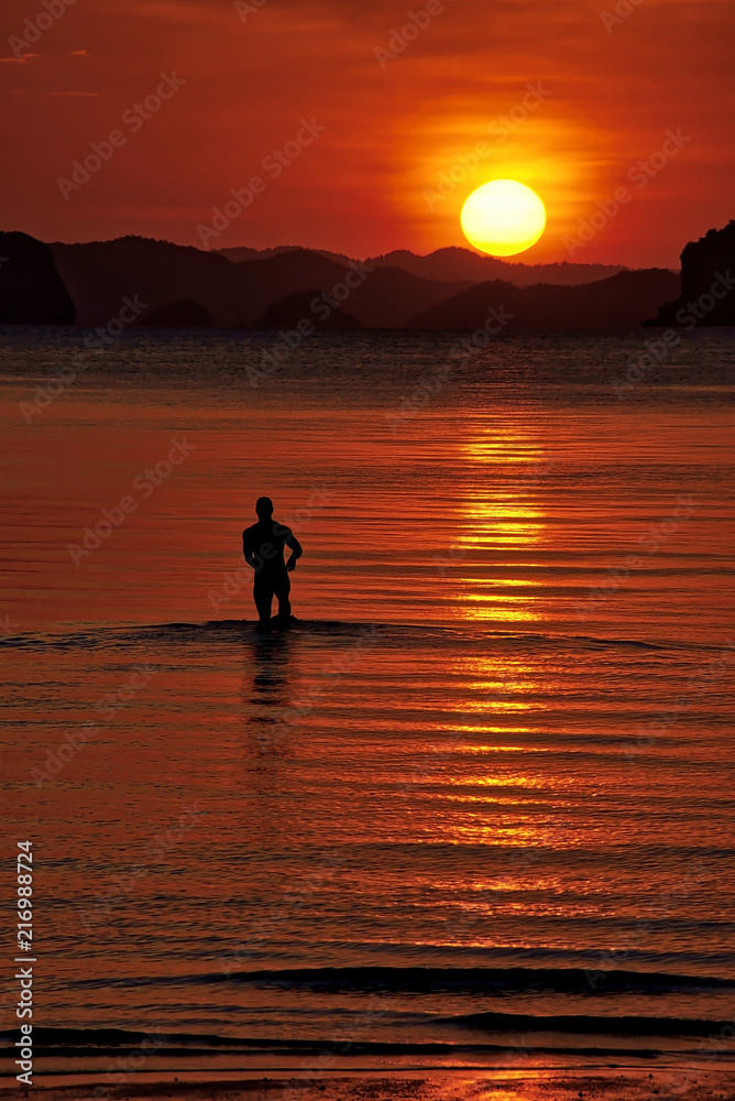 A man walks into the sea at sunset at Krabi, Thailand