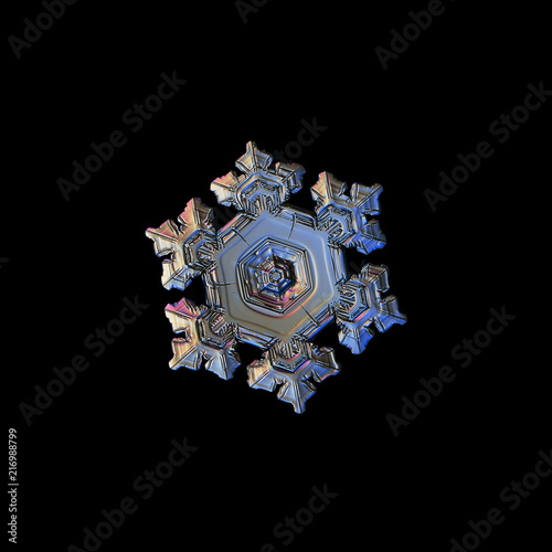 Snowflake isolated on black background. Macro photo of real snow crystal: beautiful star plate with fine hexagonal symmetry, six short, broad arms and glossy relief surface with complex inner details.