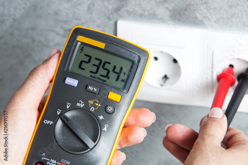 Woman checking voltage in power socket photo