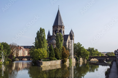Grey french castle in Metz in the summer day with green trees around it near the river