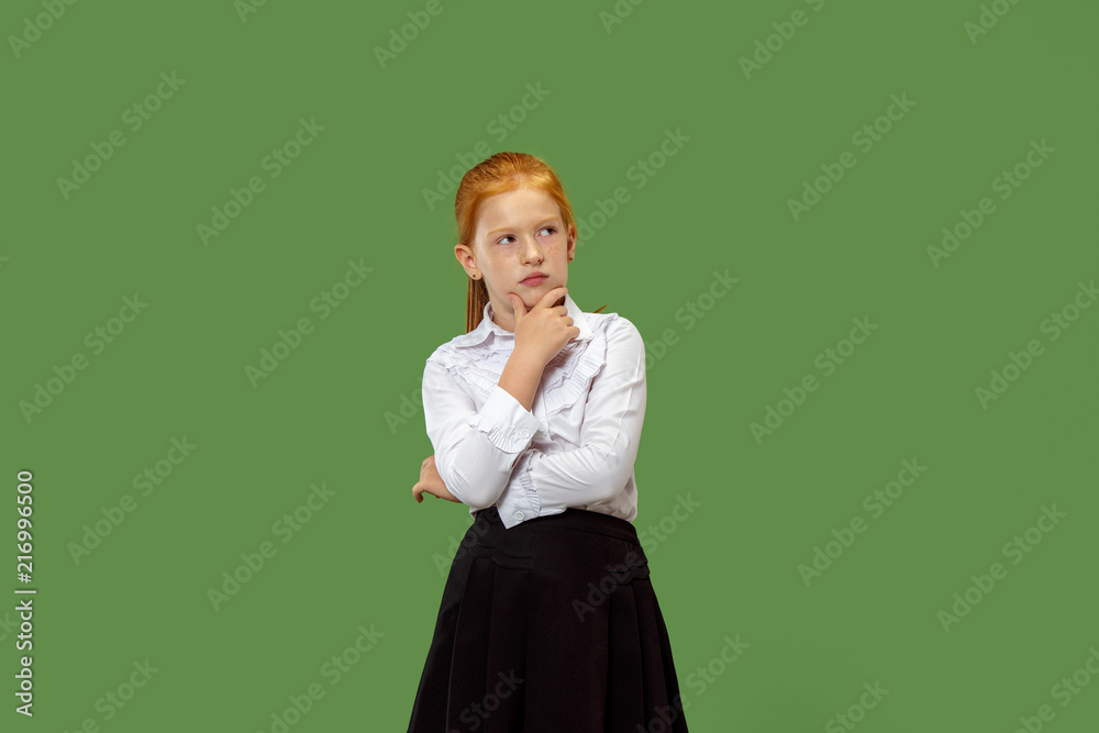 Serious doubtful, thoughtful, bored teen girl remembering something. Young emotional woman. Human emotions, facial expression concept. Studio. Isolated on trendy green. Front Serious doubtful, thoughtful, bored teen girl remembering something. Young emotional woman. Human emotions, facial expression concept. Studio. Isolated on trendy green. Front