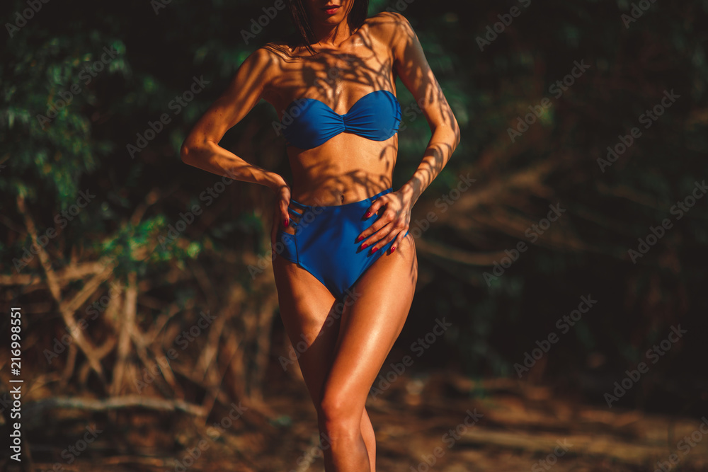 Fototapeta premium Beautiful young woman in a bikini in the shade under the tree