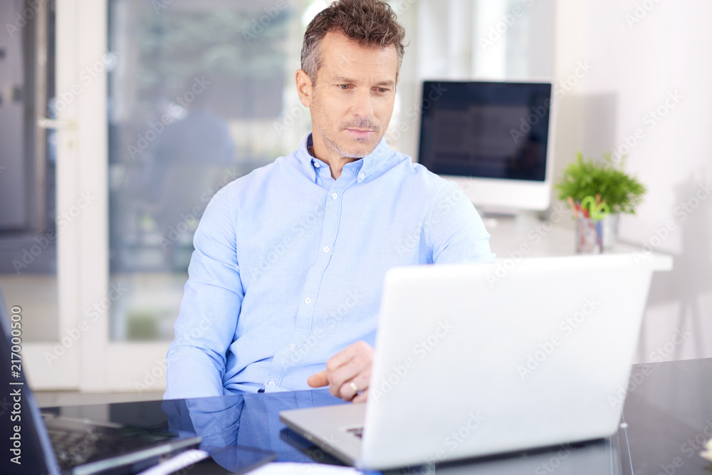 Successful in business life. Middle aged businessman with laptop in the office Successful in business life. Middle aged businessman with laptop in the office