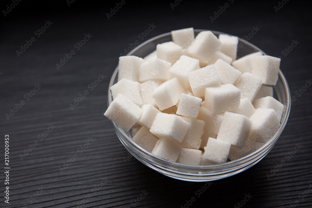 White sugar cubes in round bowl on black background with copy space, food ingredient White sugar cubes in round bowl on black background with copy space, food ingredient
