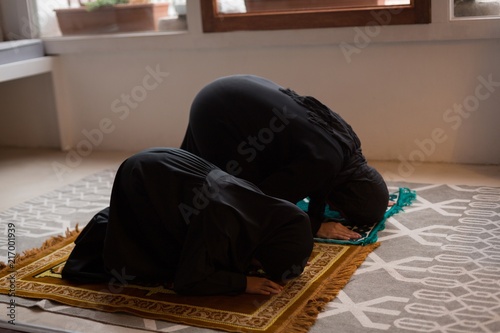 Mother and daughter praying salah at home photo