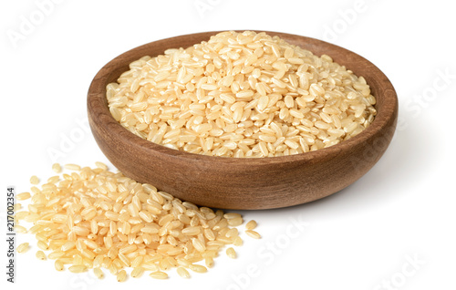 raw brown rice in the wooden plate, isolated on the white background