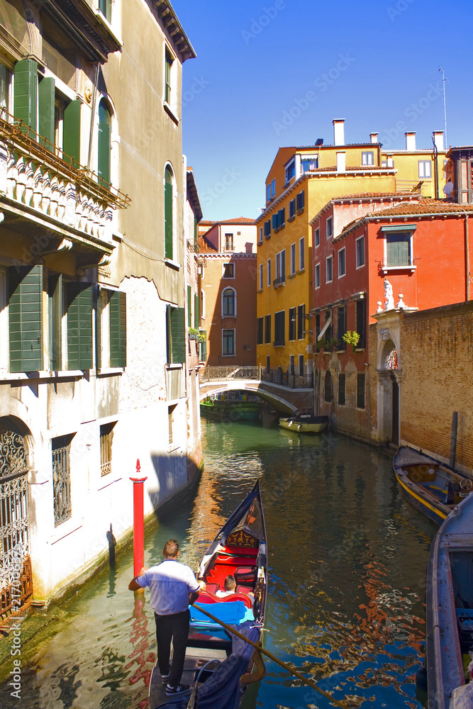  Romantic venetian cityscape with gondolas on canal in Venice Italy