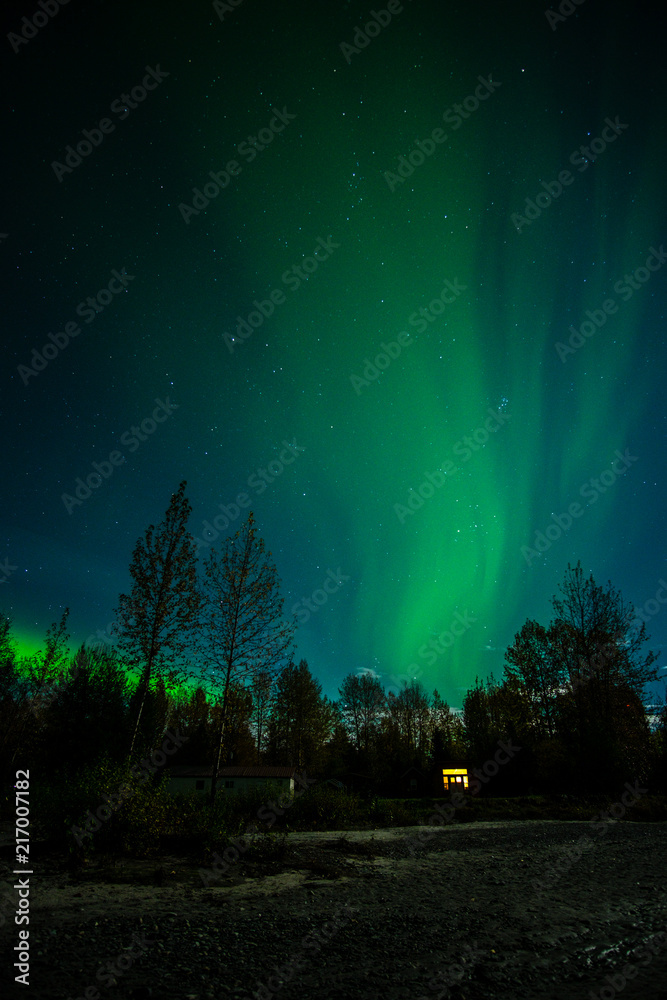 Northern light/aurora over lighting cabin in Talkeetna, Alaska. Green sky with a stars. Northern light/aurora over lighting cabin in Talkeetna, Alaska. Green sky with a stars.