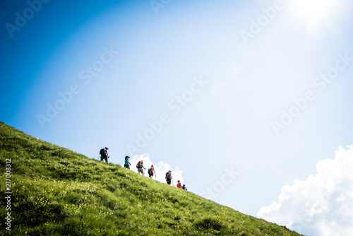Climbers walking in a green valley under a blue sky