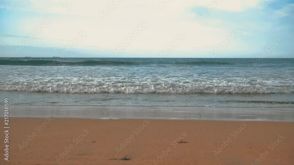 Atlantic ocean waves with foam, orange sand, and dramatic clouds blue sky Atlantic ocean waves with foam, orange sand, and dramatic clouds blue sky