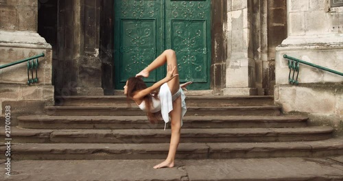 Full-length view of the graceful flexible 10 years old girl performing ballet tricks outdoor. 4k.
