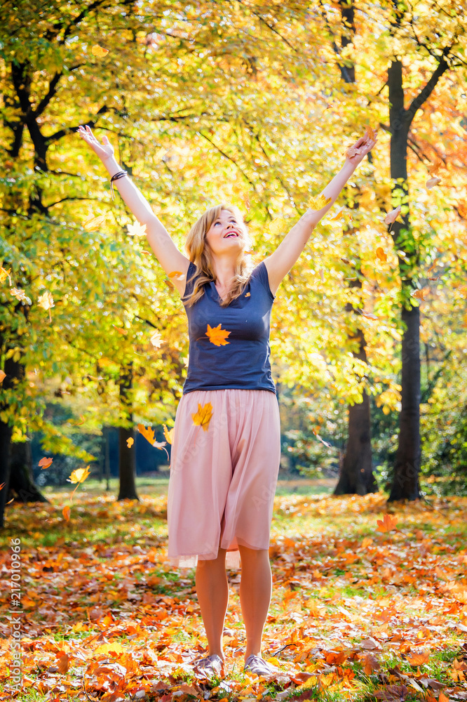 young woman throw autumn leaves in the air. Fall season forest in a sunny day young woman throw autumn leaves in the air. Fall season forest in a sunny day