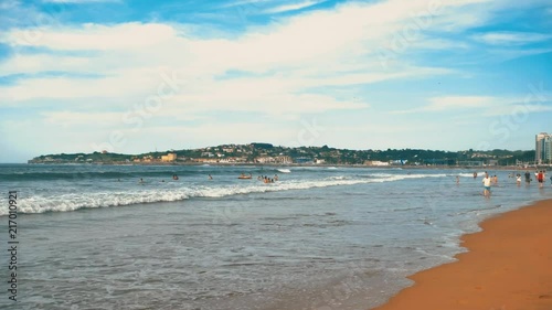 Atlantic ocean waves with foam, orange sand, and dramatic clouds blue sky photo