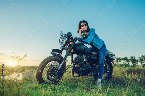 Young woman drive with motorcycle on street, enjoying freedom and active lifestyle, having fun on a bikers tour on sunset background.