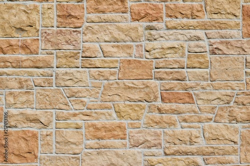 Aged fossiliferous limestone brick wall background in shades of orange, pink, yellow, and beige photo