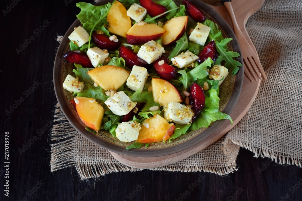 Fruit salad with arugula, plums, nectarines and soft cheese on a plate Fruit salad with arugula, plums, nectarines and soft cheese on a plate