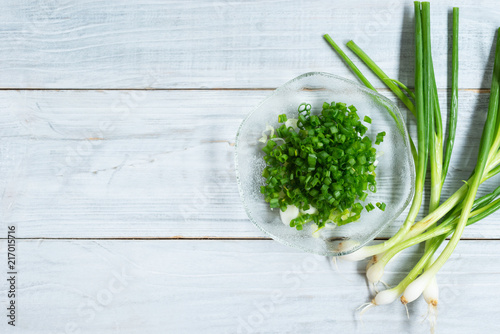 chopped fresh spring onion on white wooden background.